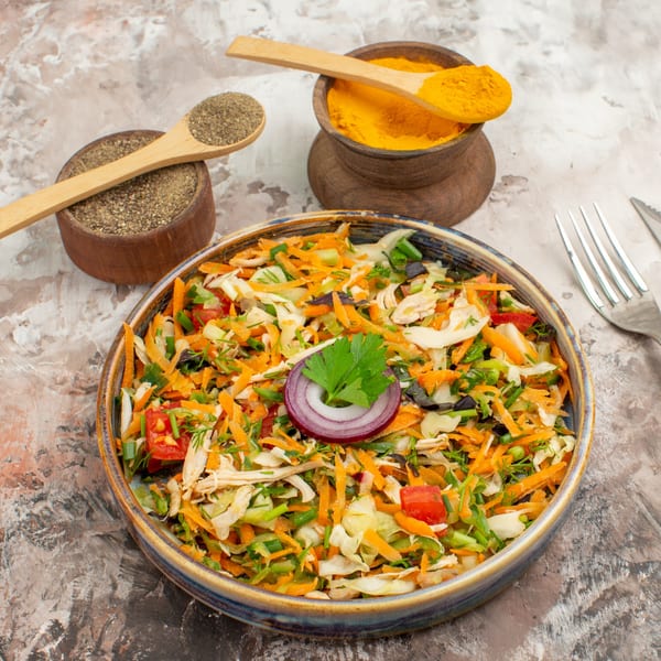 A vibrant Indian salad with shredded carrots, cabbage, and herbs, garnished with red onion and parsley.